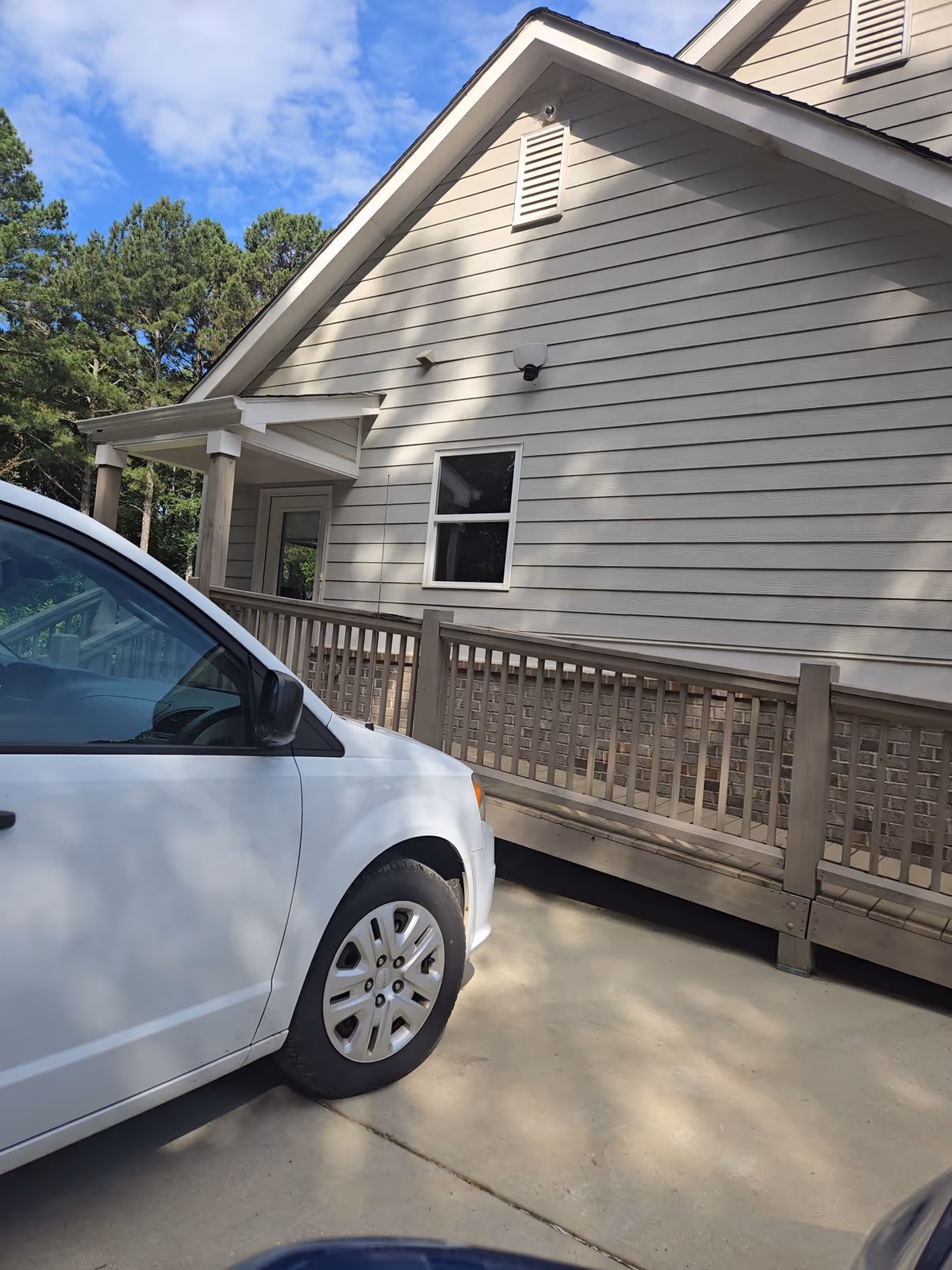 White car parked beside a beige senior living facility with a wooden ramp.