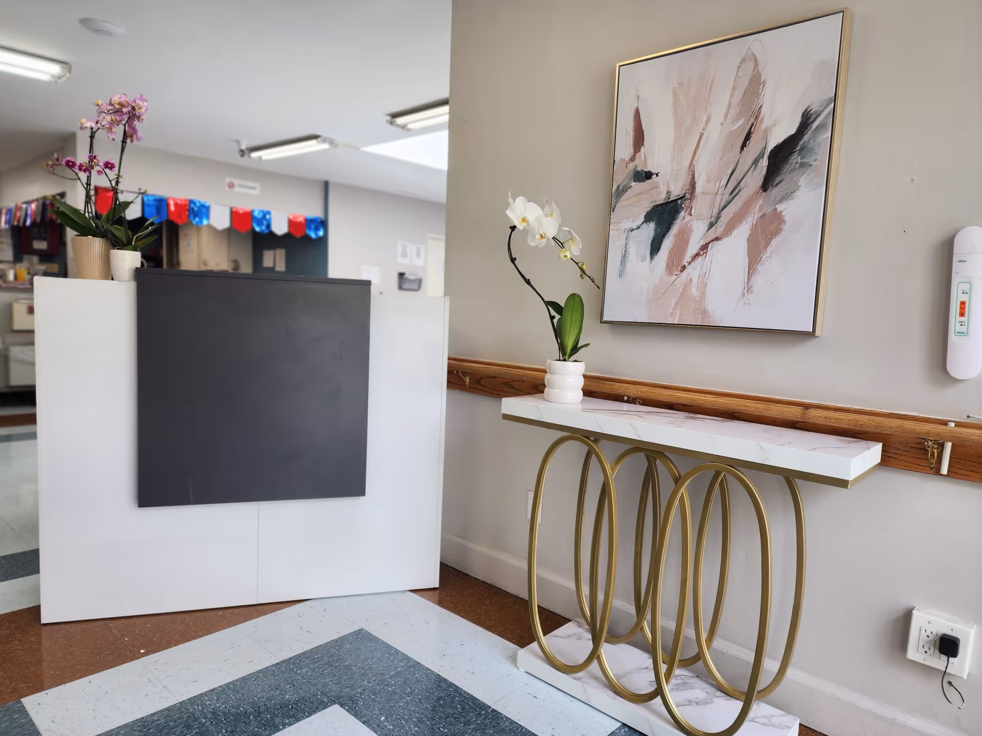 Bright reception area with white reception desk, orchid plant, and abstract wall art.