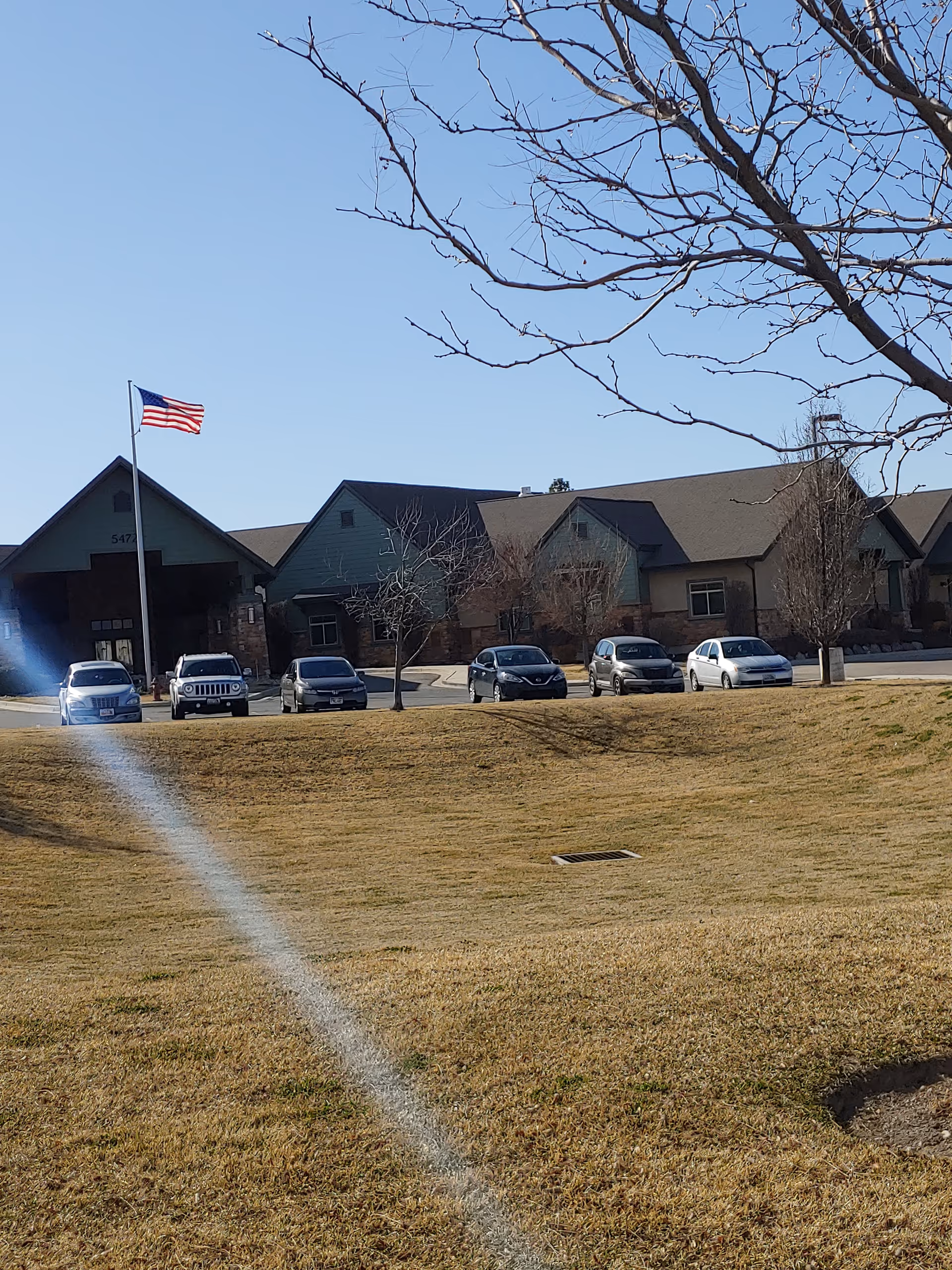 American flag beside a senior living facility building with parked cars.