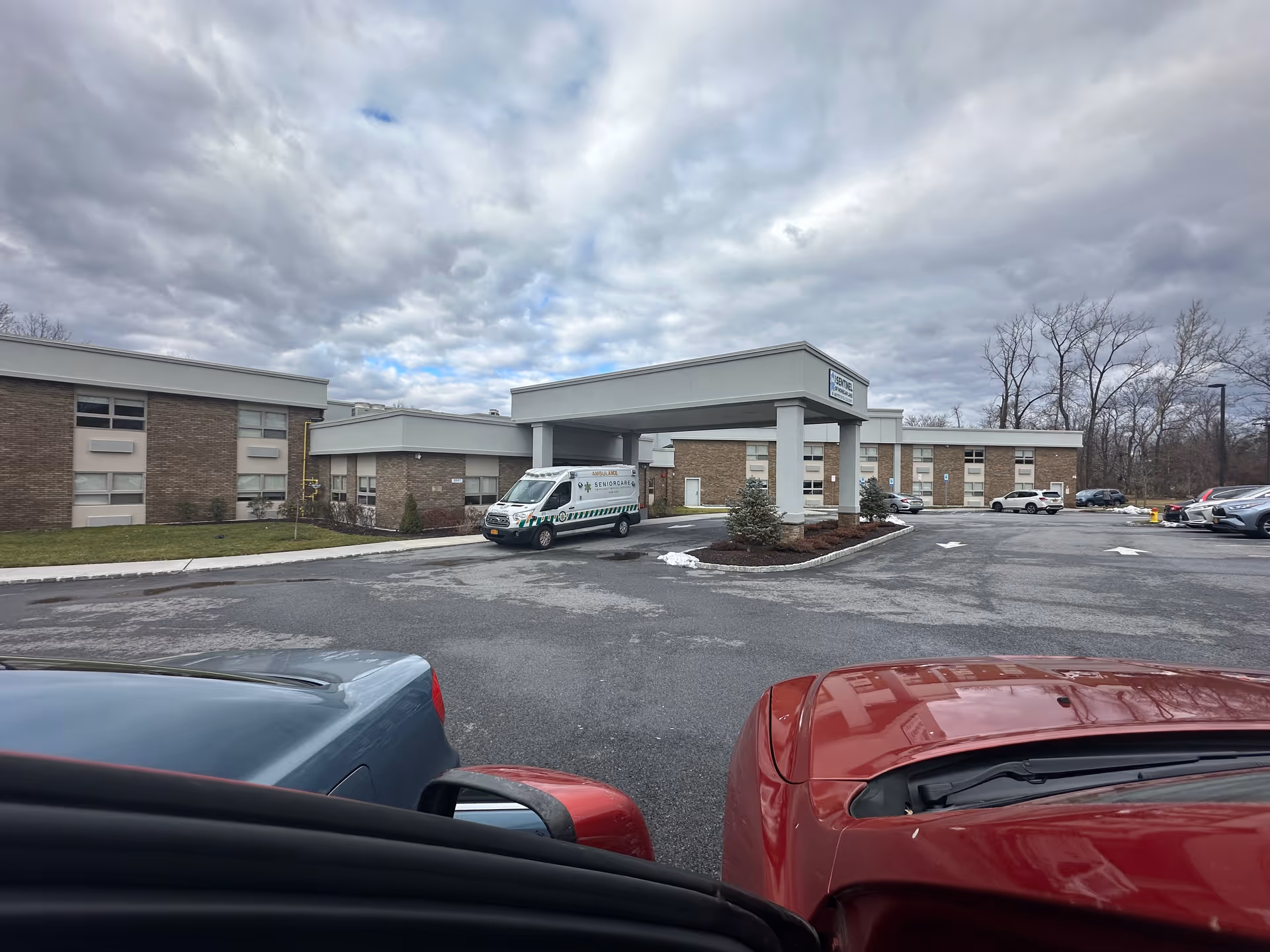 Exterior view of Mohegan Park senior living facility with a covered entrance and parking.