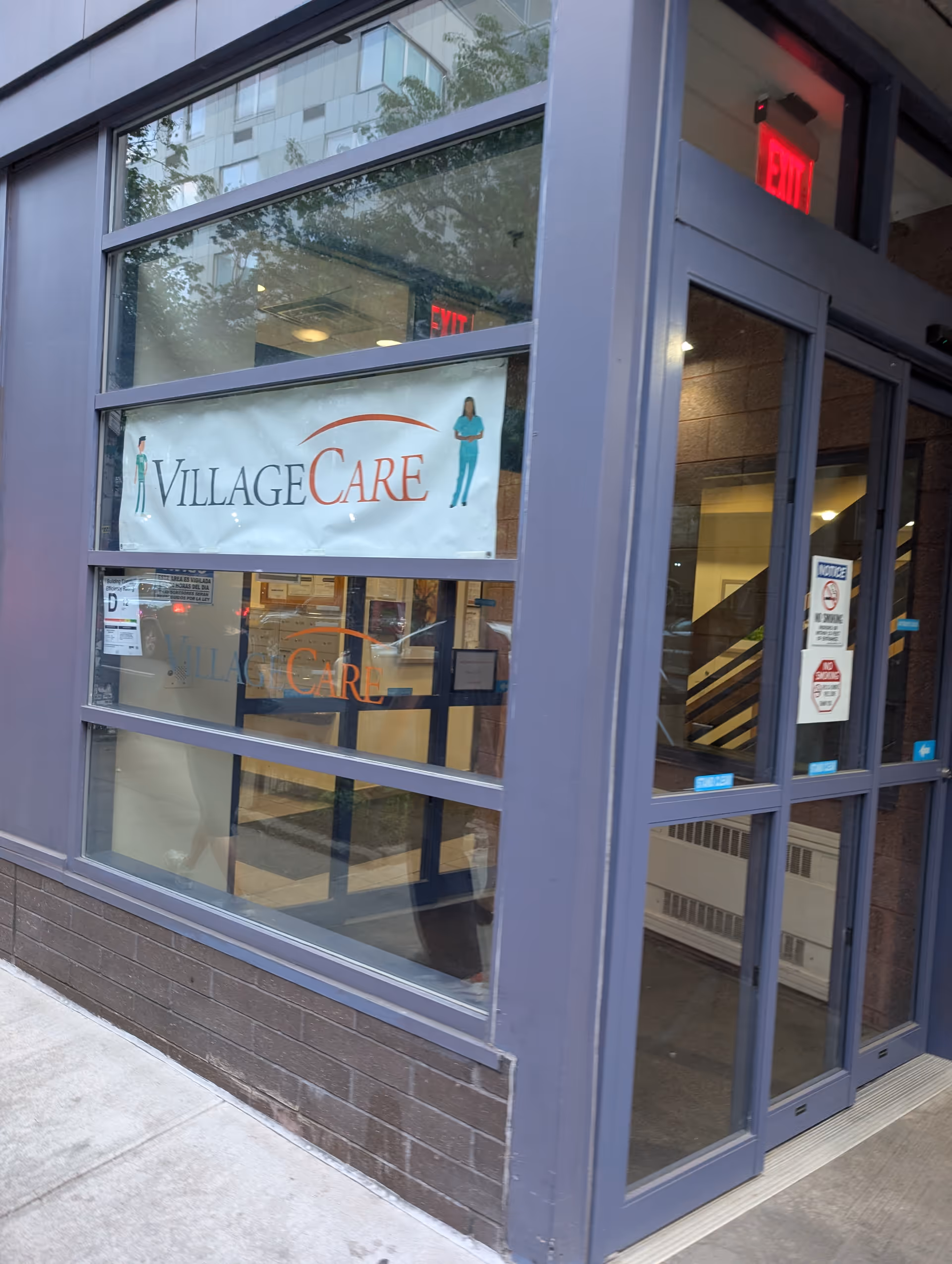 Exterior building entrance with a VillageCare banner displayed on glass storefront.