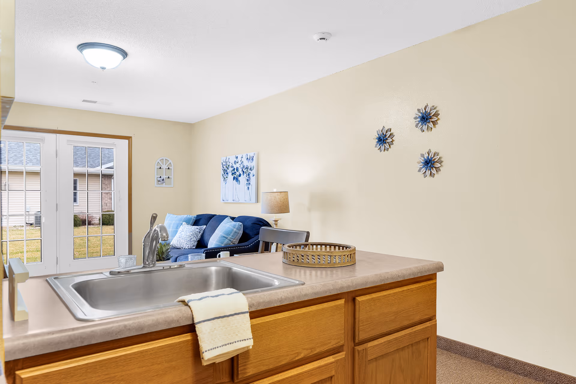 Open kitchen island with sink overlooks a living room with blue cushions