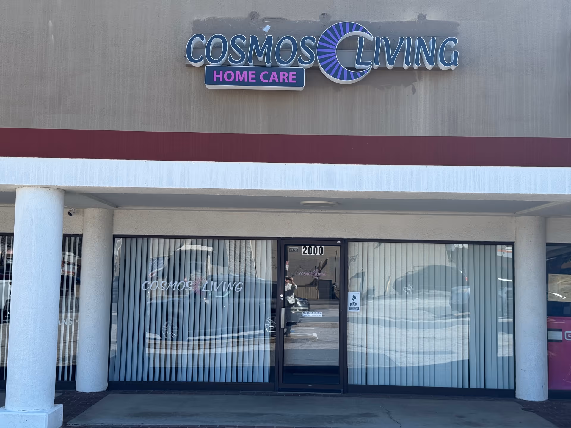 Cosmos Living Home Care storefront with glass doors and vertical blinds.