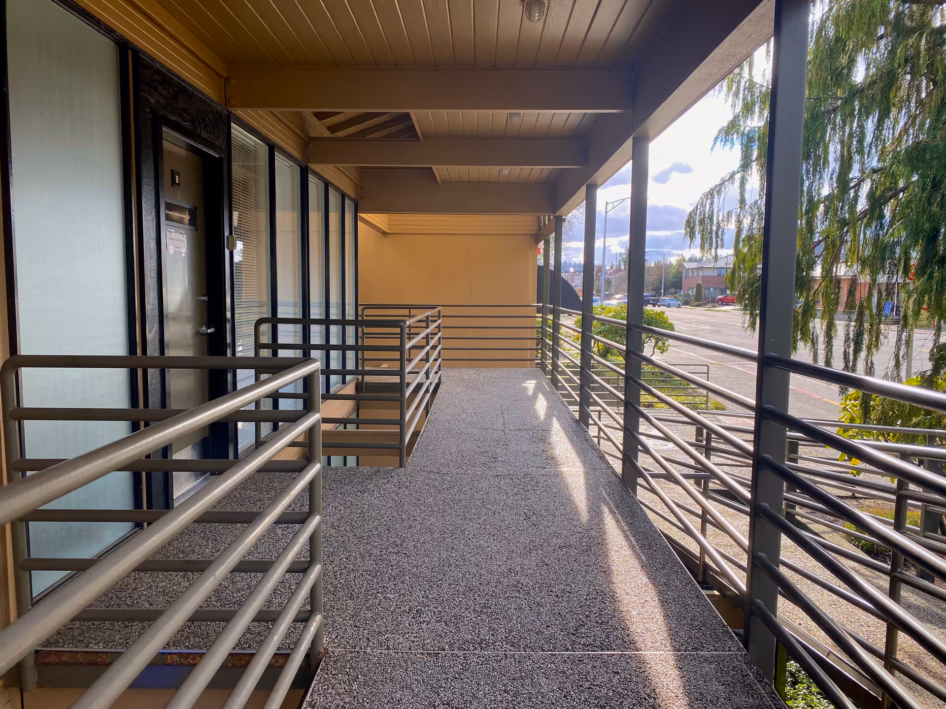 Exterior elevated walkway with metal railings along a senior living facility.