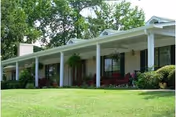 Single-story Windsor Cottage exterior with a long covered porch and manicured lawn.