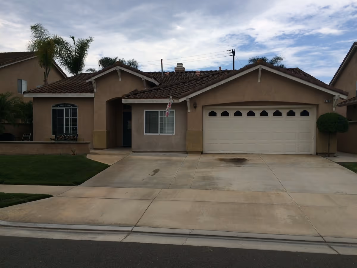 Front exterior of a beige, single-story building with a two-car garage and driveway.