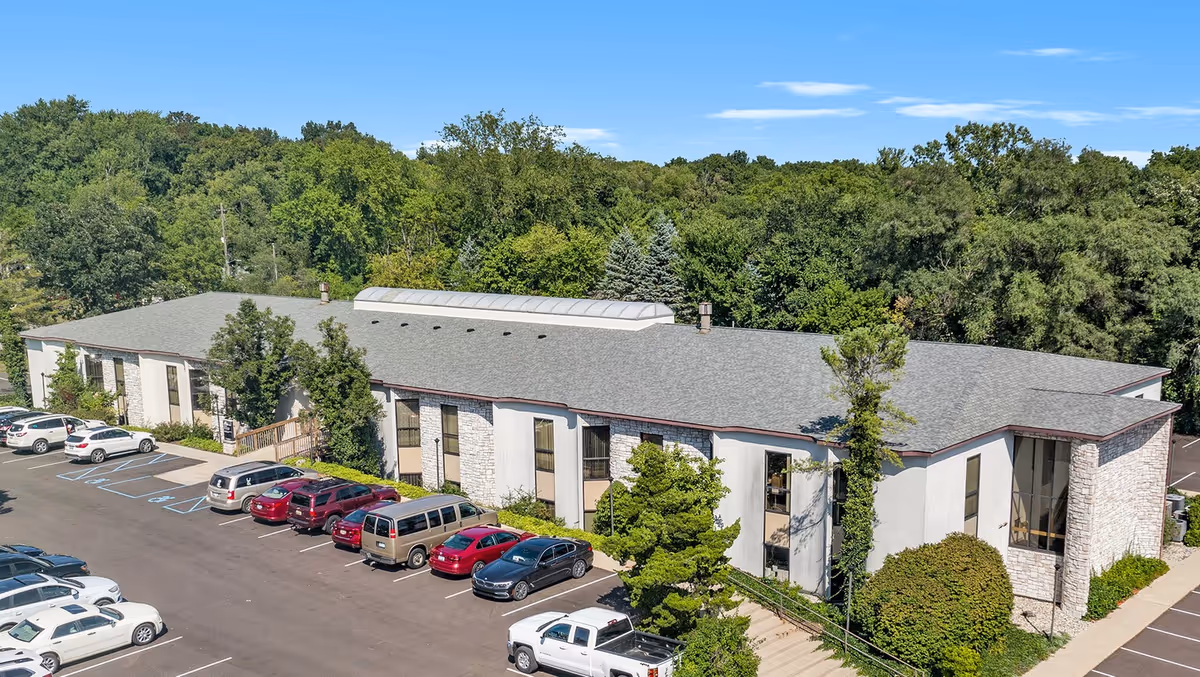 Exterior view of Optimal Care facility with parking and surrounding trees
