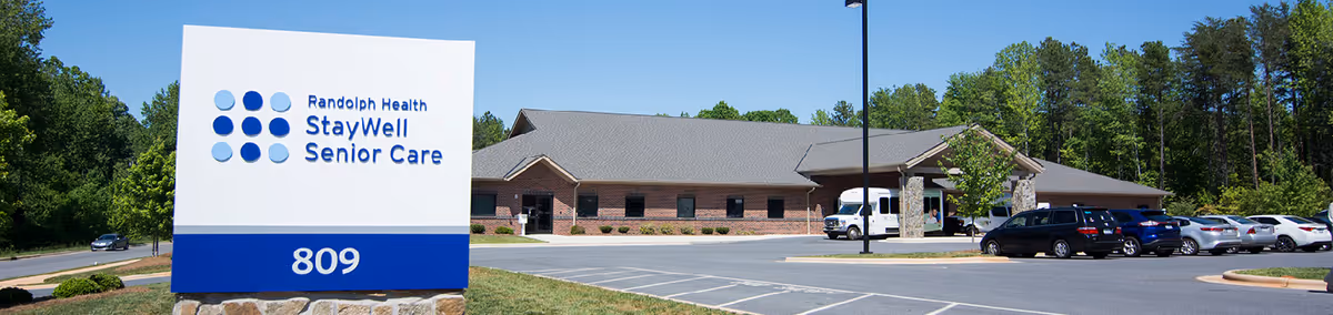 Exterior view of Randolph Health StayWell Senior Care facility with sign and parking lot.