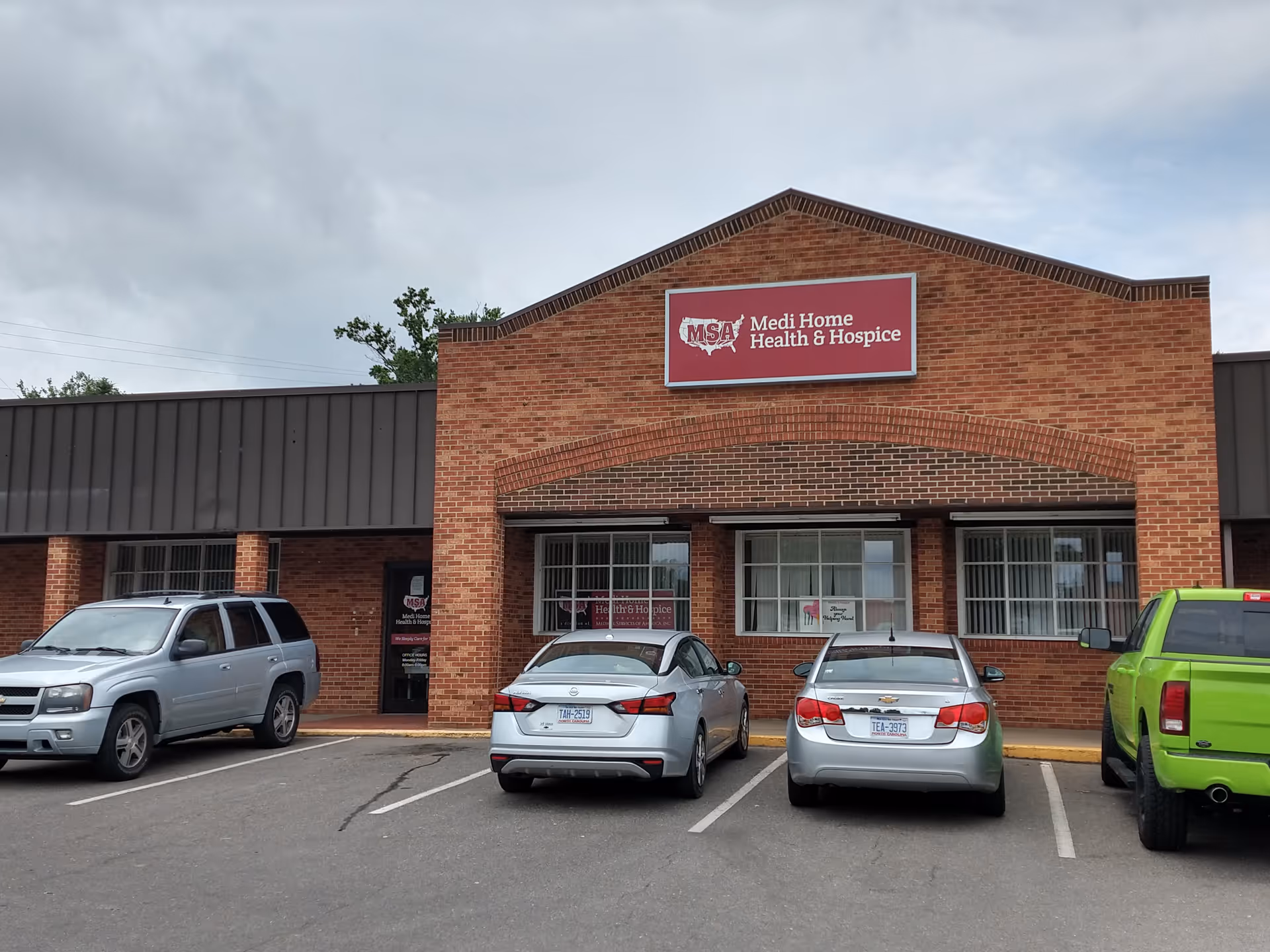 Brick building with Medi Home Health & Hospice sign, and a parking lot full of cars.