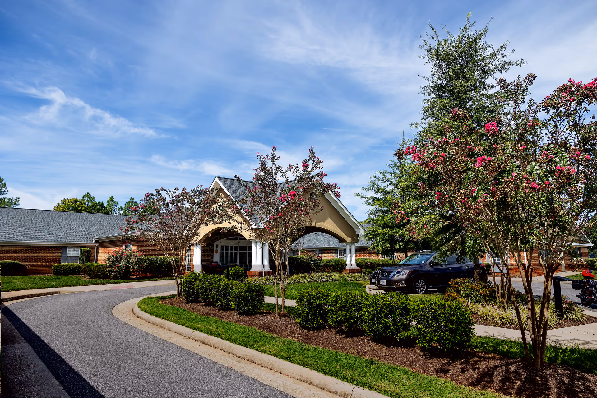 Exterior view of Commonwealth Senior Living at Chesterfield with curved driveway and landscaped entrance.