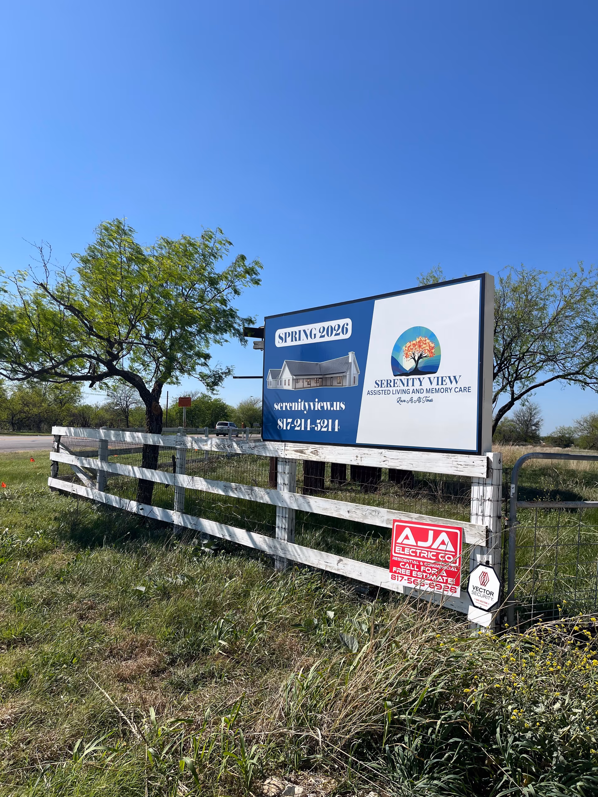 A large Serenity View billboard beside a wooden fence under a clear blue sky.