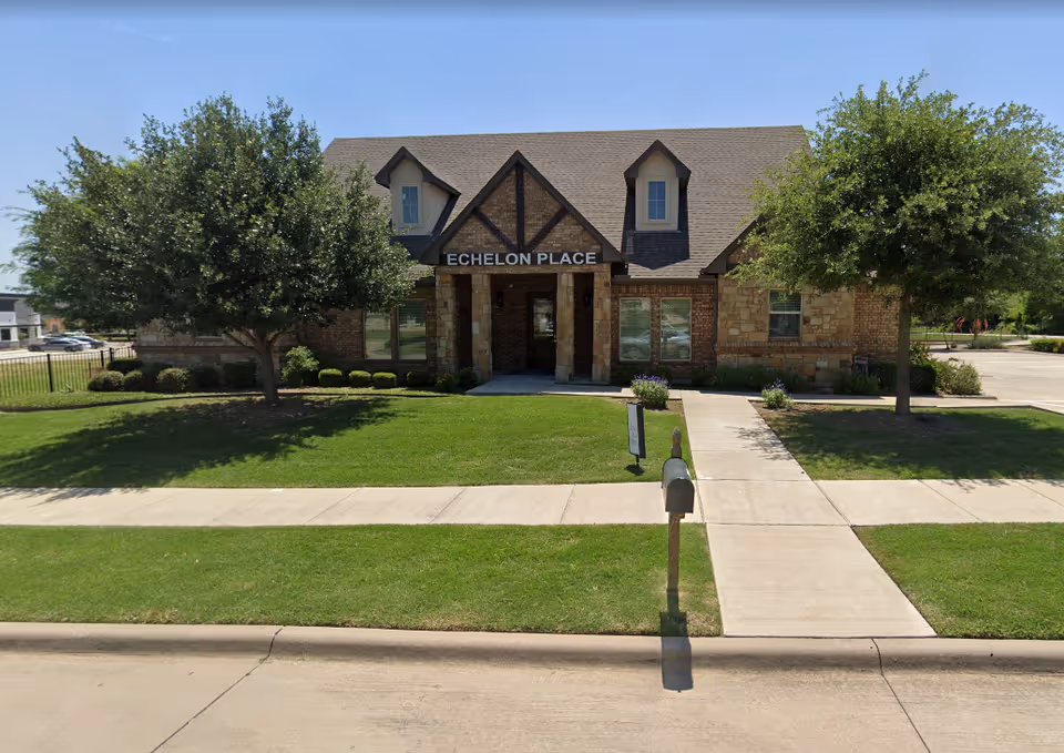 Front view of Echelon Place Assisted Living building with lawn and trees