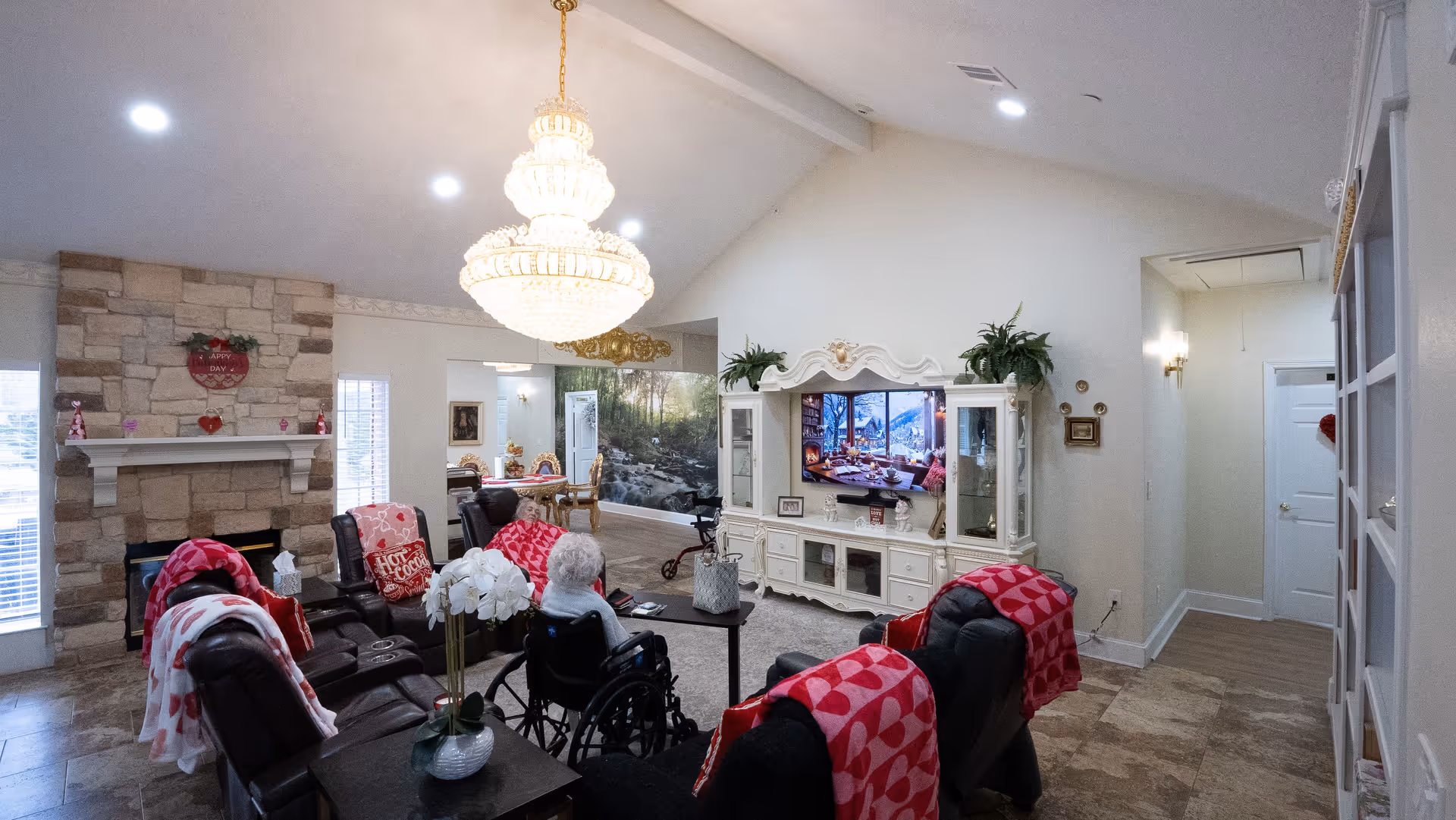 Elegant living room in a senior facility with chandelier, stone fireplace, and residents seated