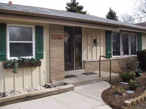 Front exterior of Ivy Terrace facility with brick, siding, green shutters, and a walkway.