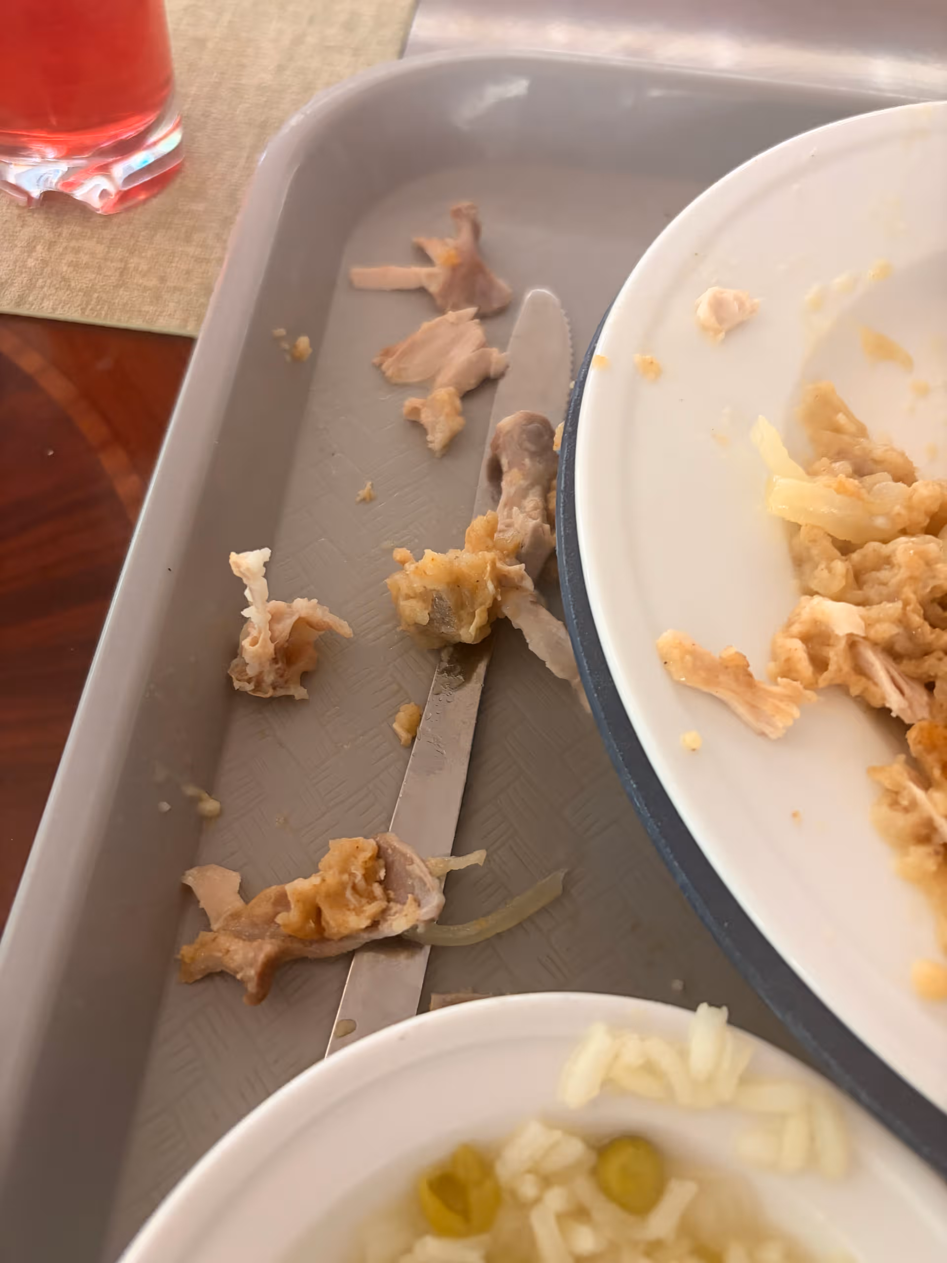 Meal remnants on a dining tray with a plate of food and a knife.
