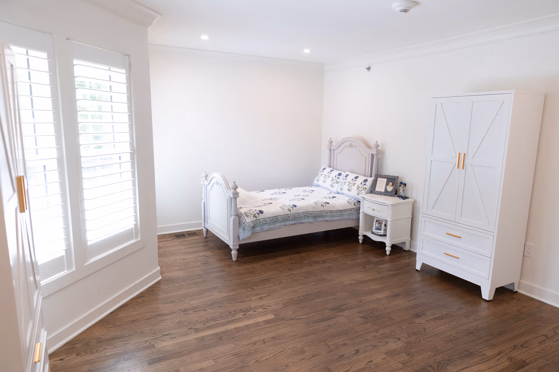 Bright white bedroom with a bed, nightstand, and wardrobe.