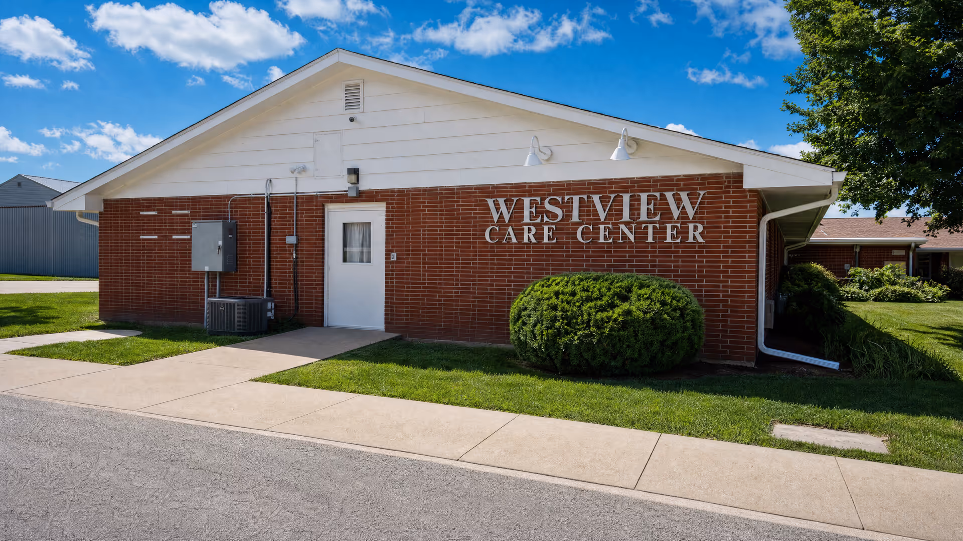 Brick building with Westview Care Center signage, front entrance, sidewalk, and neatly trimmed shrubs.