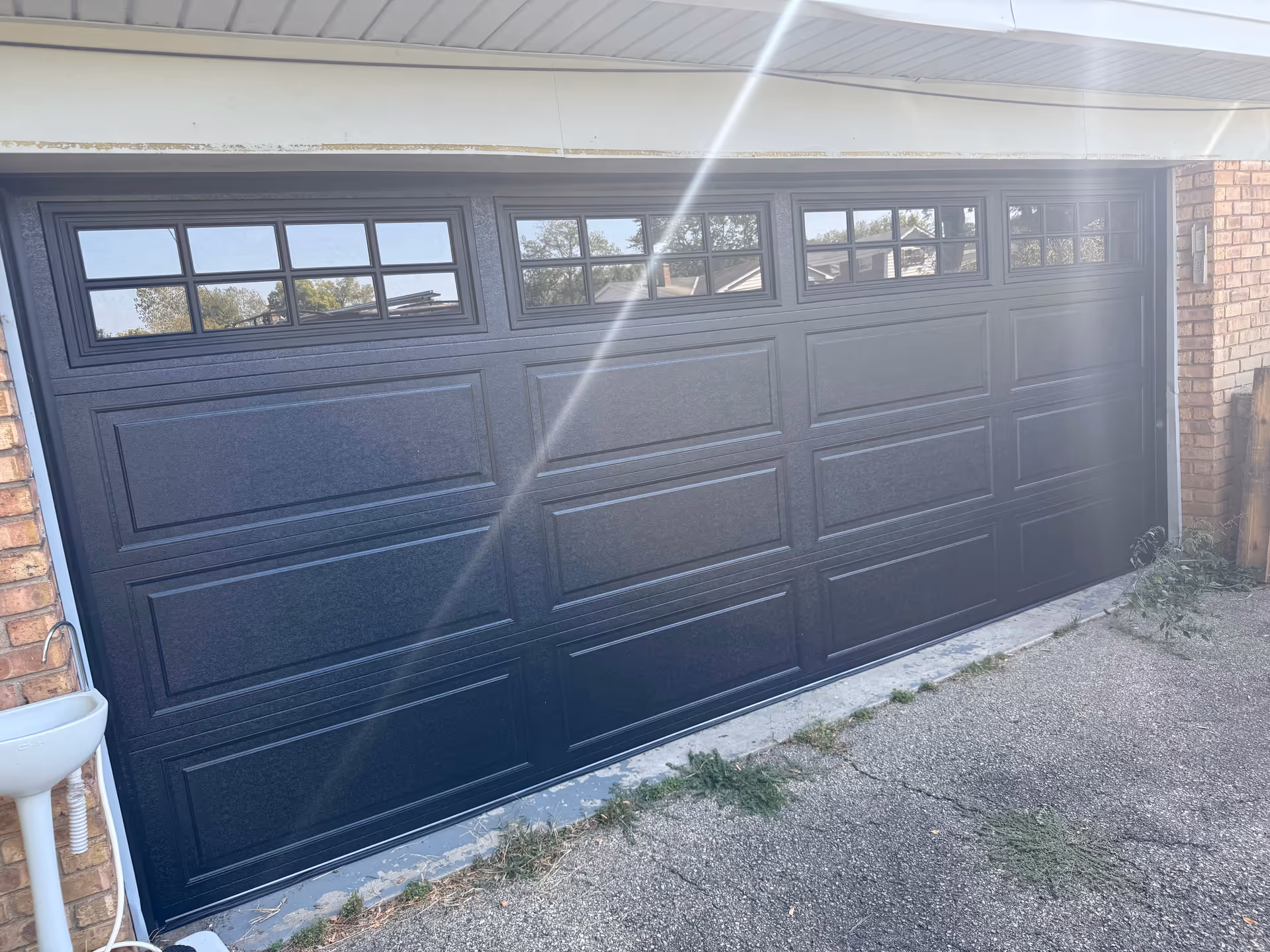 A dark garage door with rectangular panels and small window panes in a brick building.