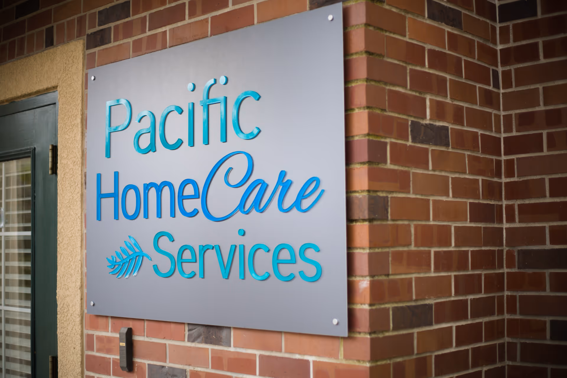 Exterior brick wall displaying a Pacific HomeCare Services sign