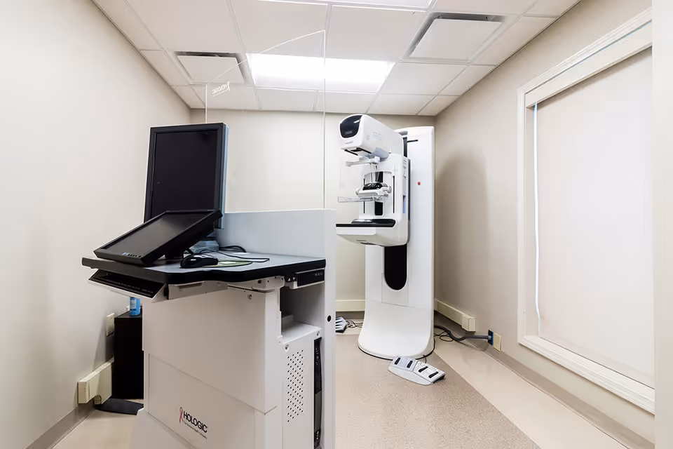 Interior of a medical imaging room with a large white scanner and workstation.