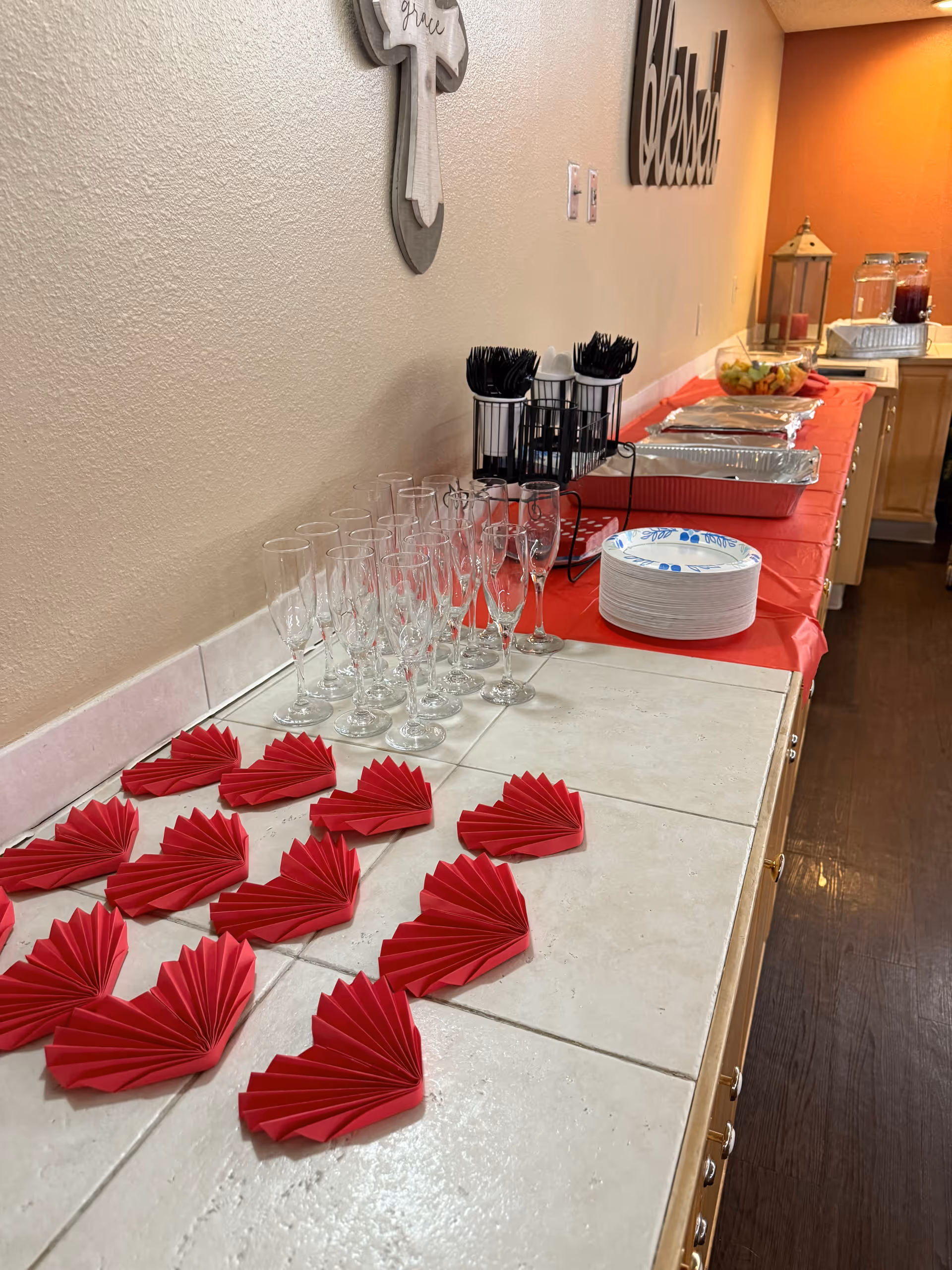 Buffet table with red folded napkins, glassware, and serving dishes in a dining area.