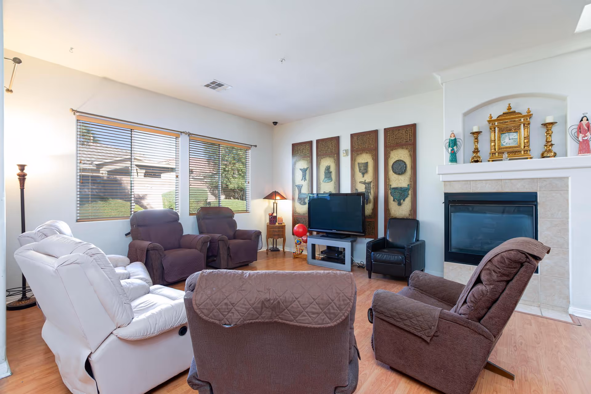 Bright senior living lounge with recliners, TV, fireplace, and large windows.