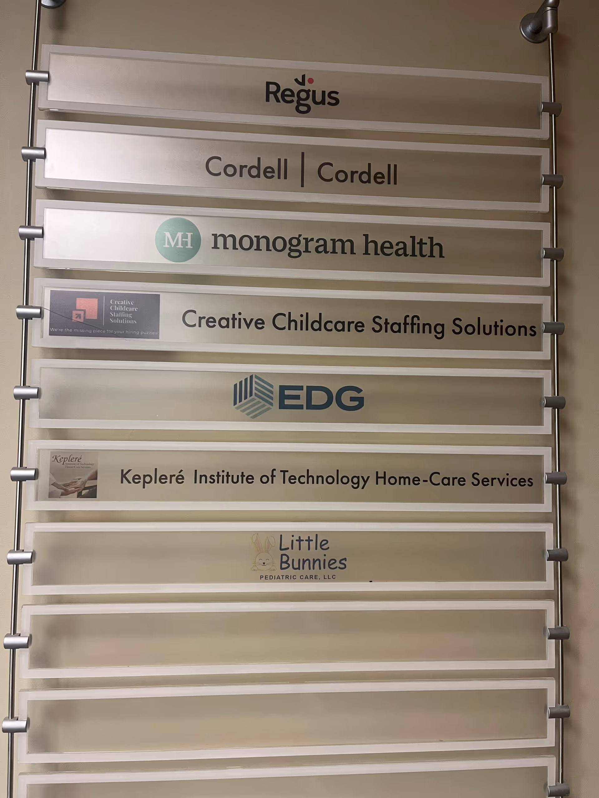 Wall-mounted signboard listing multiple care service logos, including Little Bunnies Pediatric Care.