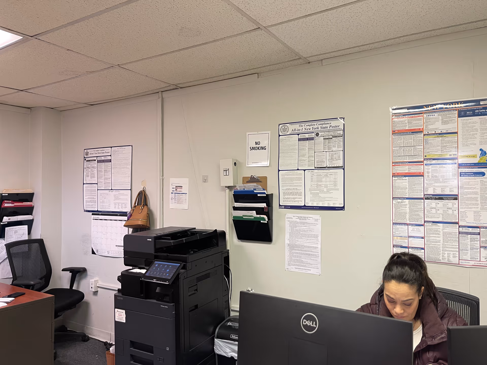 Office workspace with a desk, printer, and wall posters in a Fidelity Home Care facility.