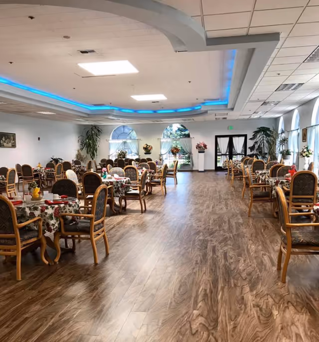 Inside a spacious dining hall with round tables, floral centerpieces, and wooden chairs.