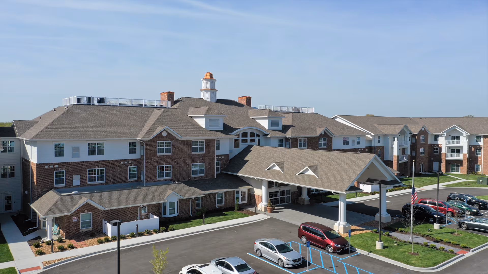 Exterior view of Creek Valley Retirement Community: brick building with a covered entrance and parking.