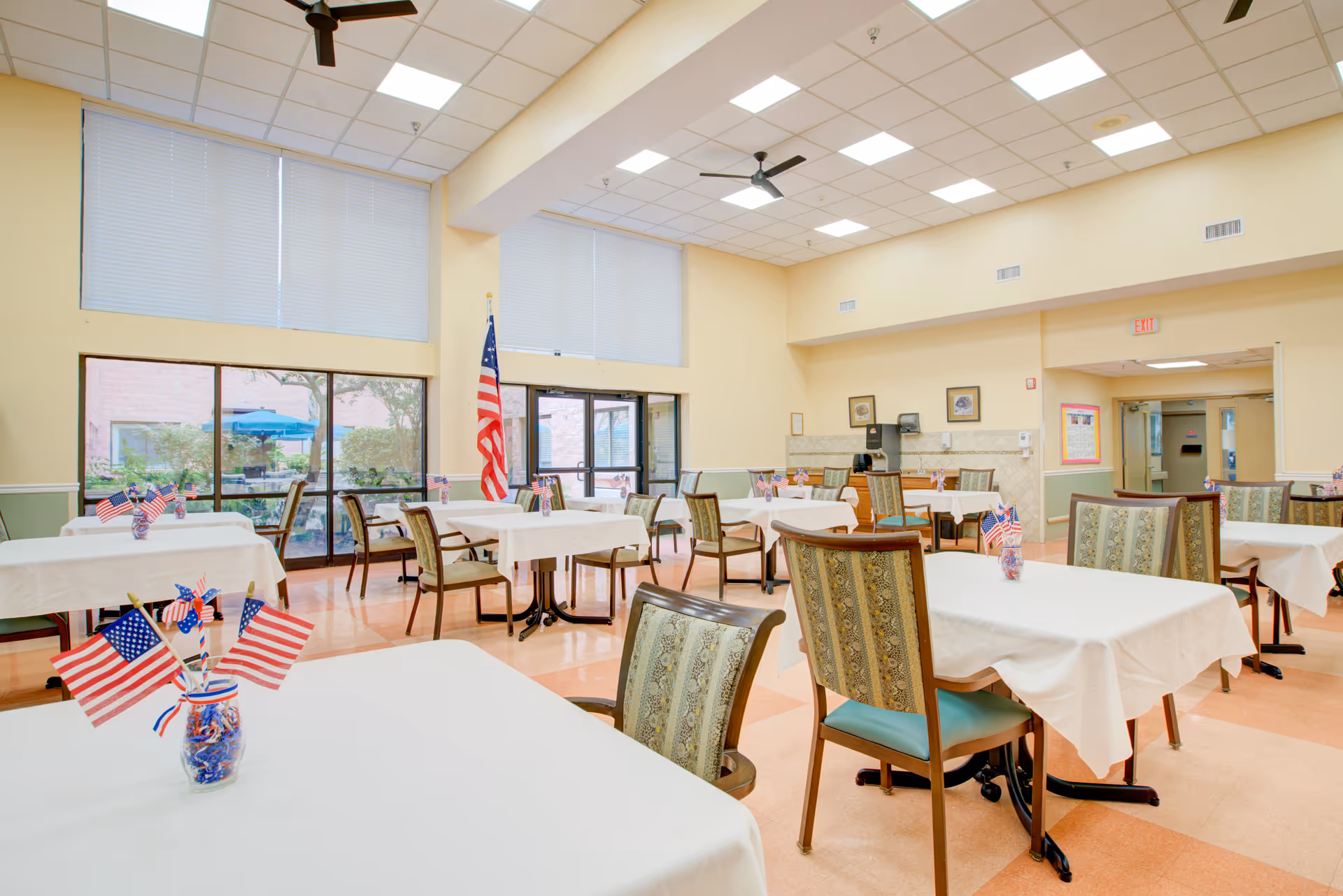 Bright dining hall with tables covered in white cloths and American flags.