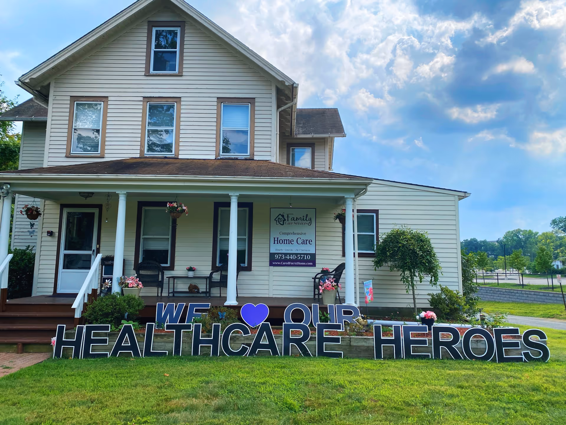 Two-story beige building with a front porch and a large lawn sign honoring healthcare heroes