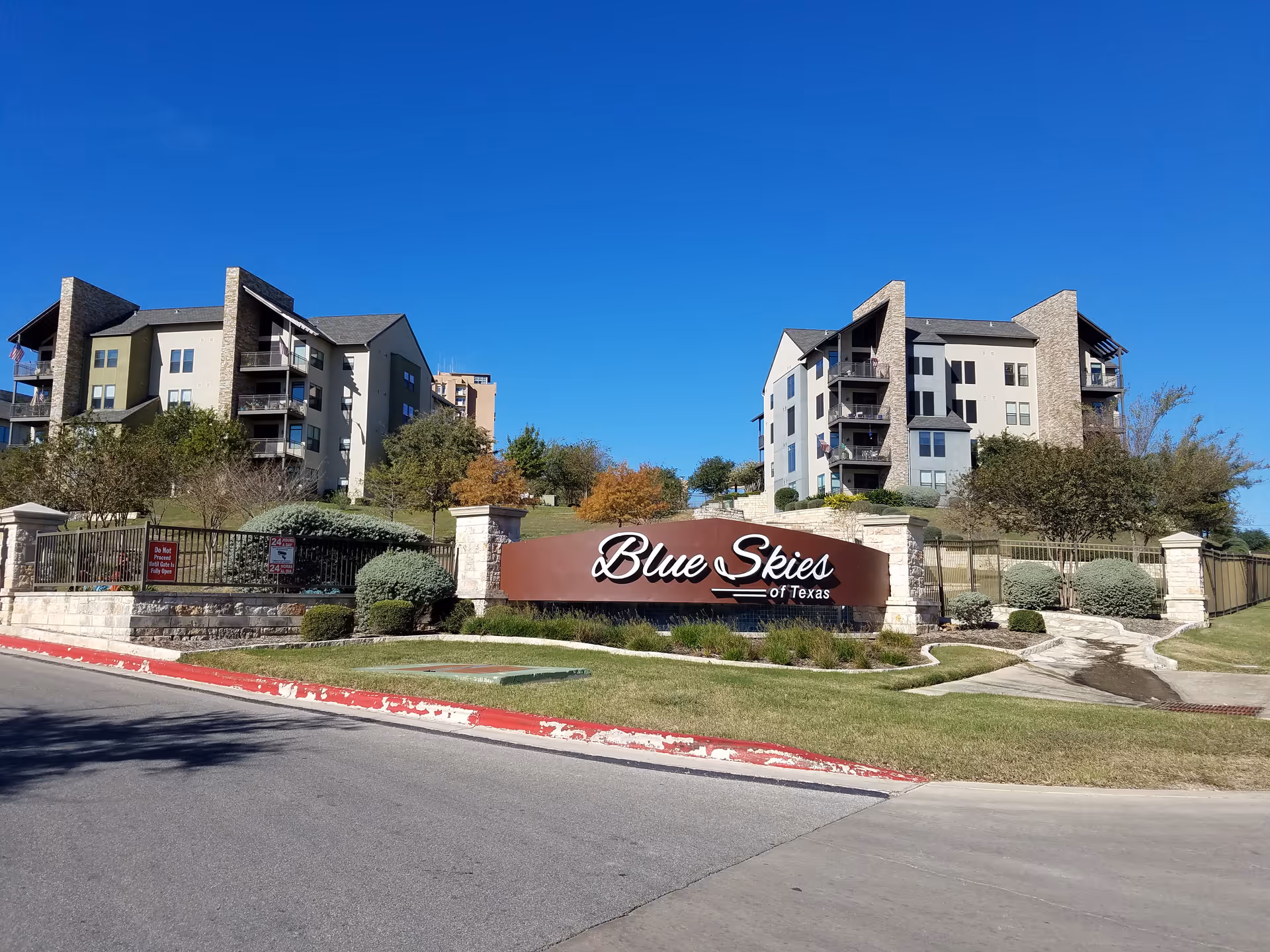 Exterior view of Blue Skies of Texas East complex with a large sign and landscaped grounds.