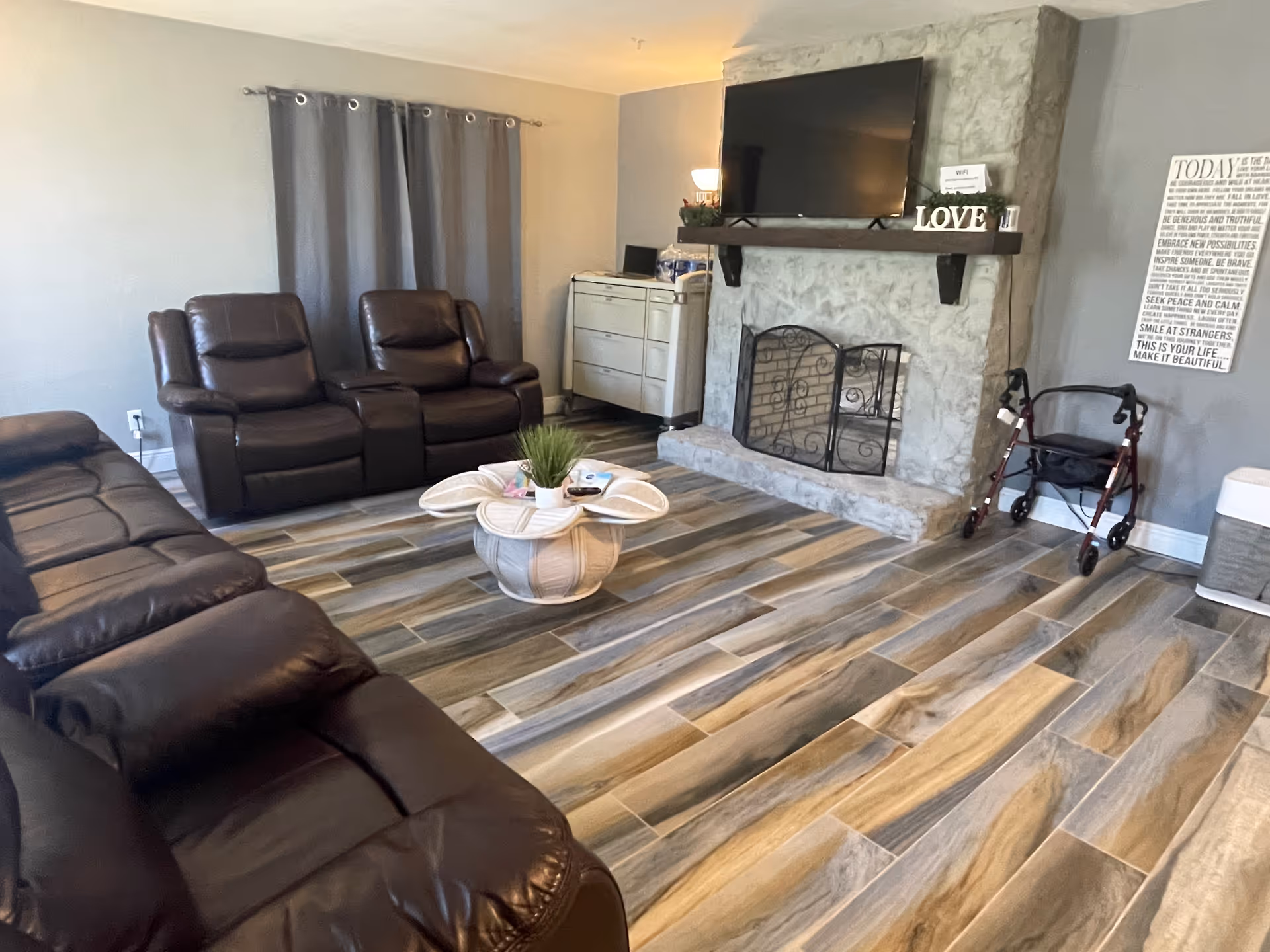 Cozy living room with leather seating, a fireplace, TV, and walker near the wall.