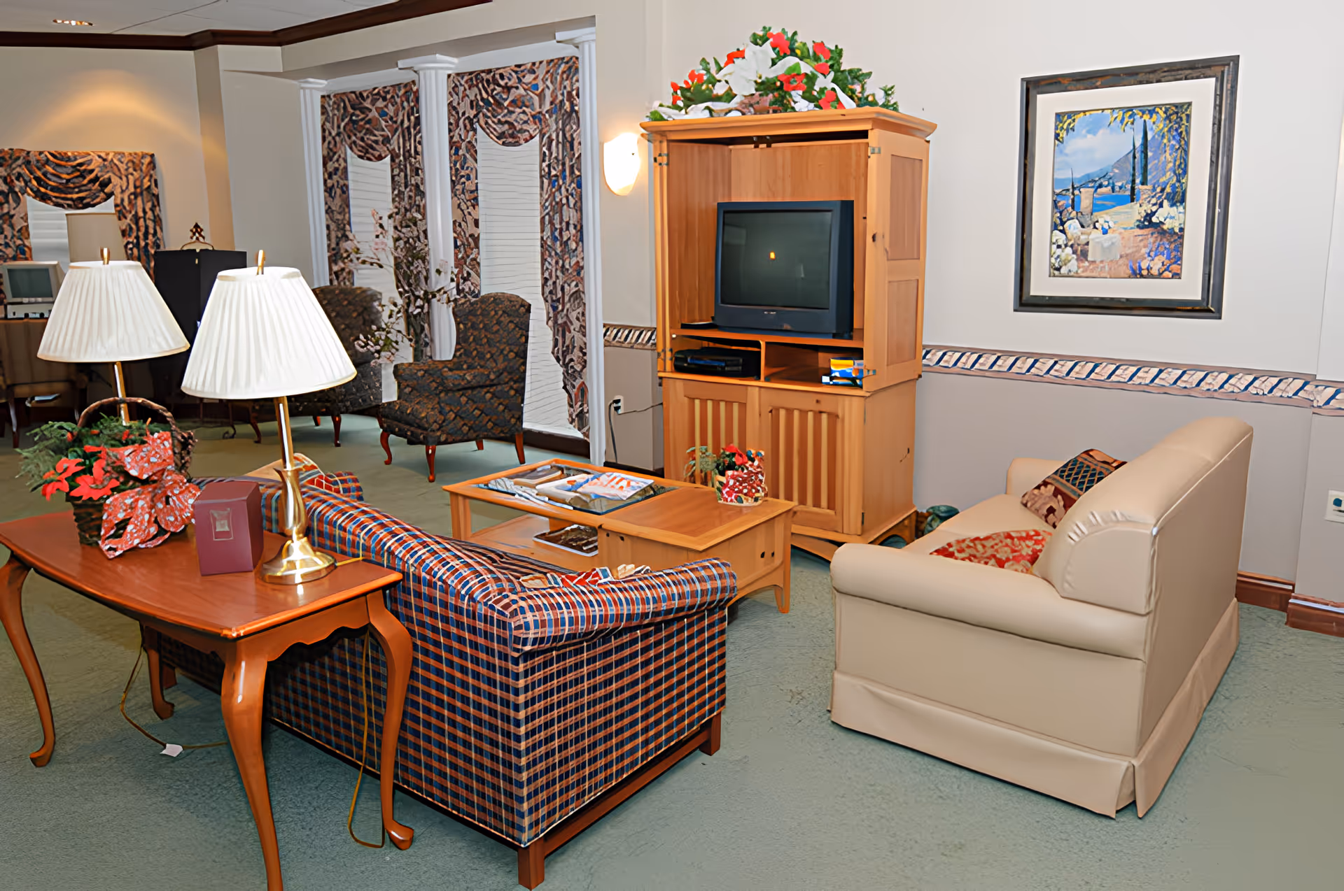 Cozy common living room with sofas, armchairs, a TV cabinet, coffee table, and table lamps.