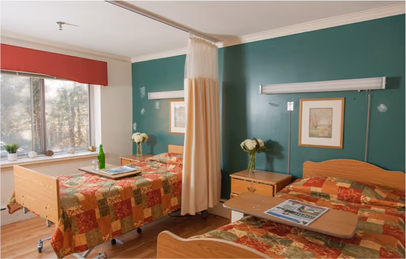 Two beds with patchwork quilts and a curtain dividing a shared bedroom.