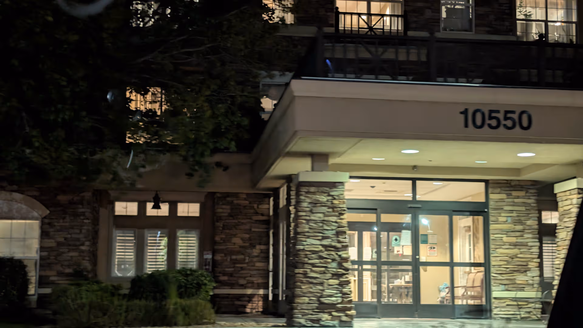 Night exterior of The Heights of Summerlin entrance with stone pillars and glass doors.