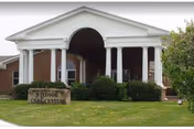 Front exterior of Windsor Care Center featuring a white portico, columns, and landscaped entrance.