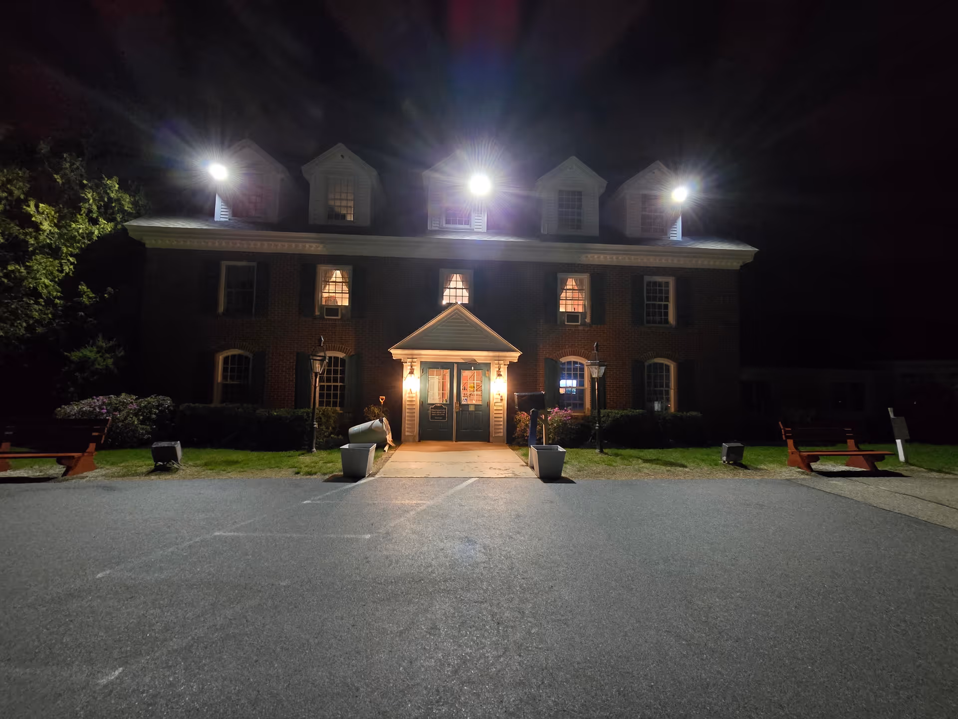 Night exterior of a brick senior living facility with a lit front entrance.