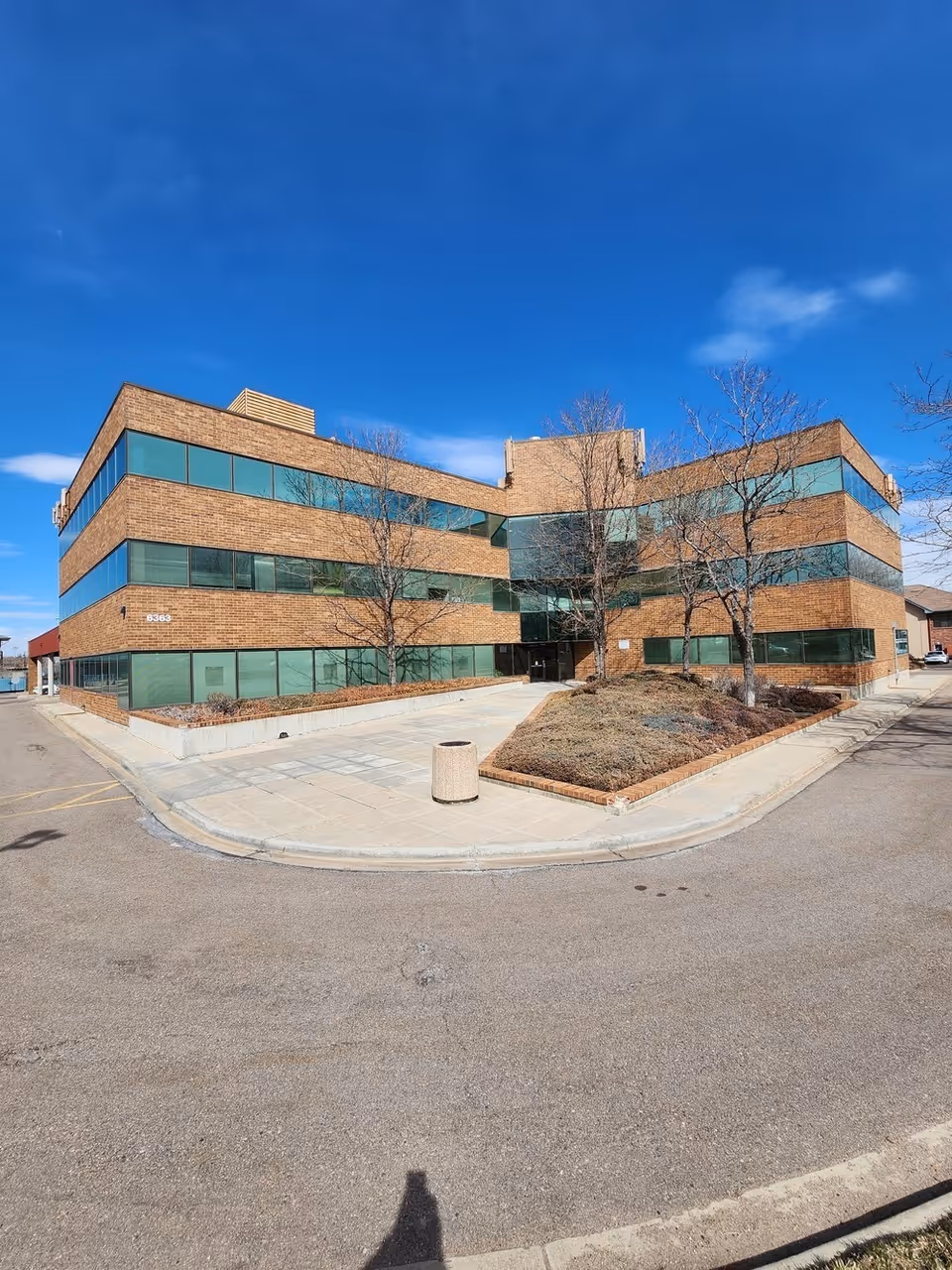 Brick, three-story building with large glass windows and a paved entrance area.