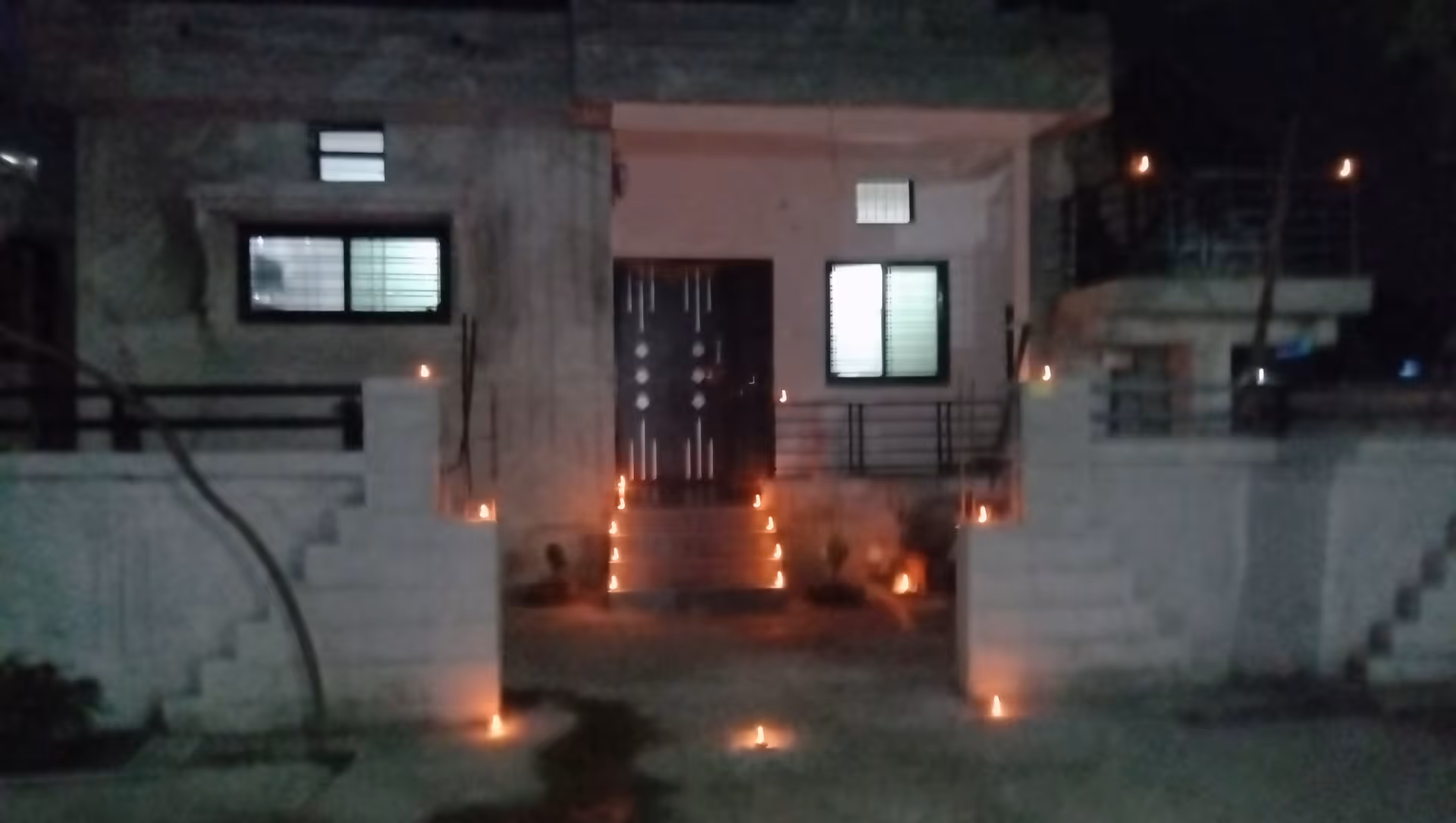 Night exterior of a home-style facility with candle-lit steps to the front entrance.