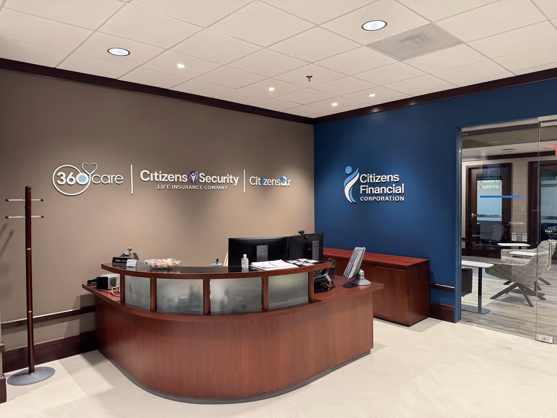 Curved wooden reception desk in a modern lobby with 360care signage on the wall.