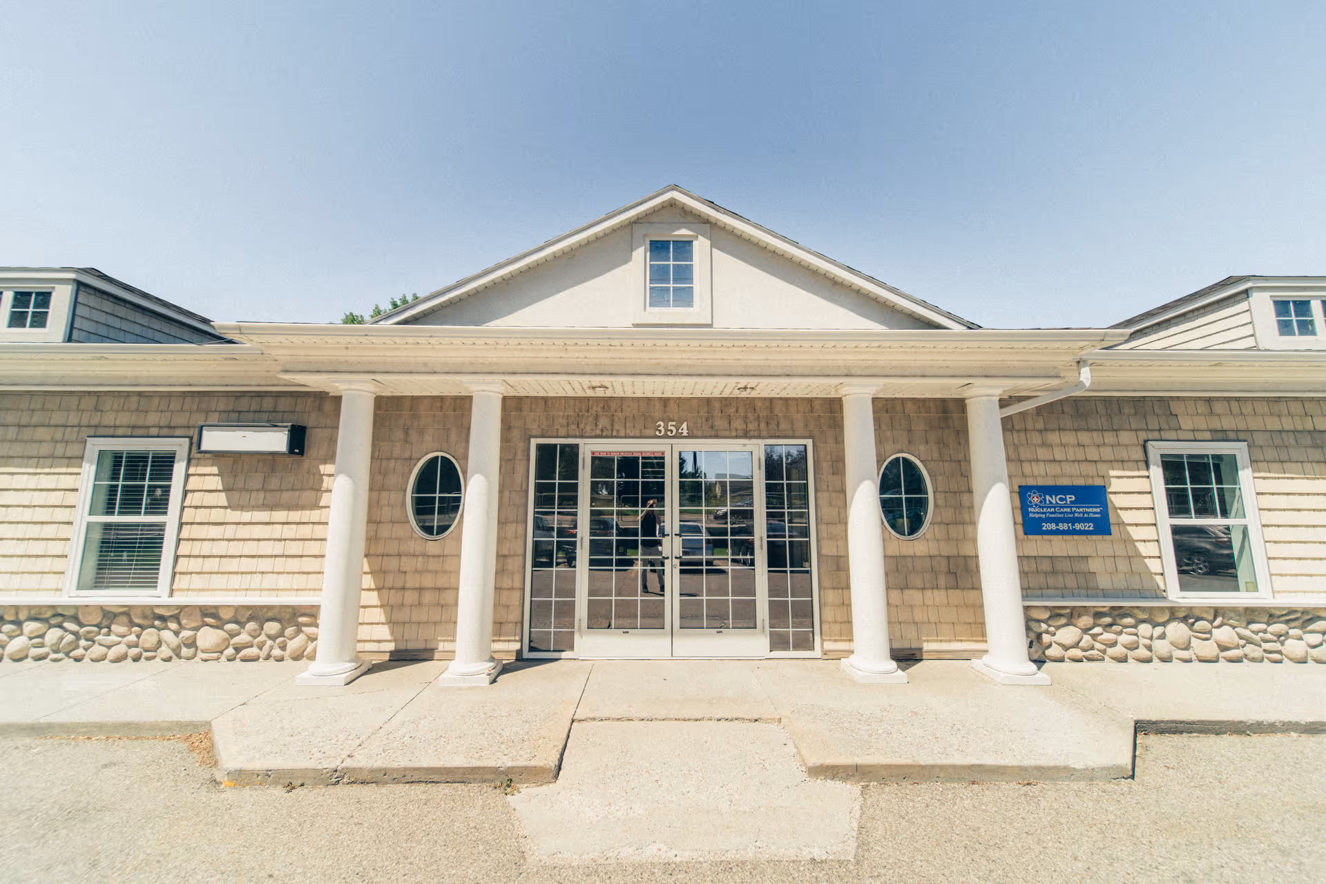 Front exterior of a beige senior care facility with glass doors and columns.