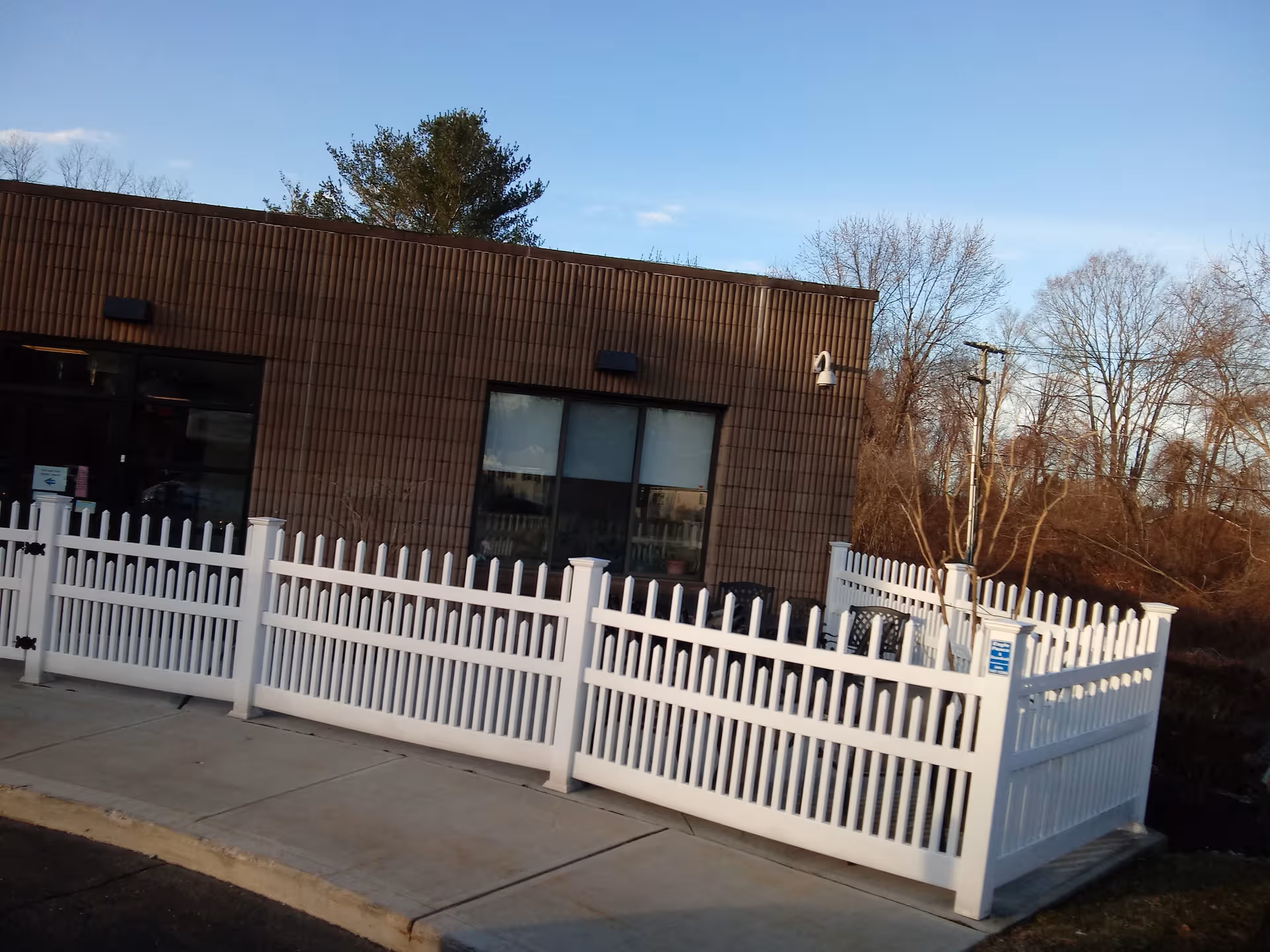 Exterior view of Vernon Rehabilitation and Healthcare Center with a white picket fence and sidewalk.