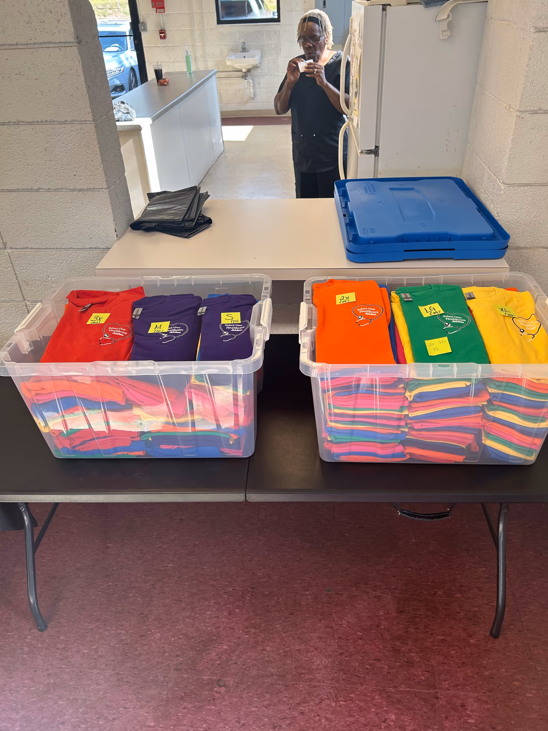 Laundry area in a senior facility with colorful shirts sorted in clear bins.