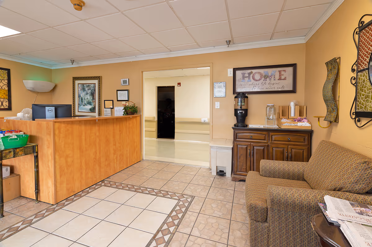 Reception/lobby area with a wooden front desk, a couch, a beverage station, and decorative wall art.