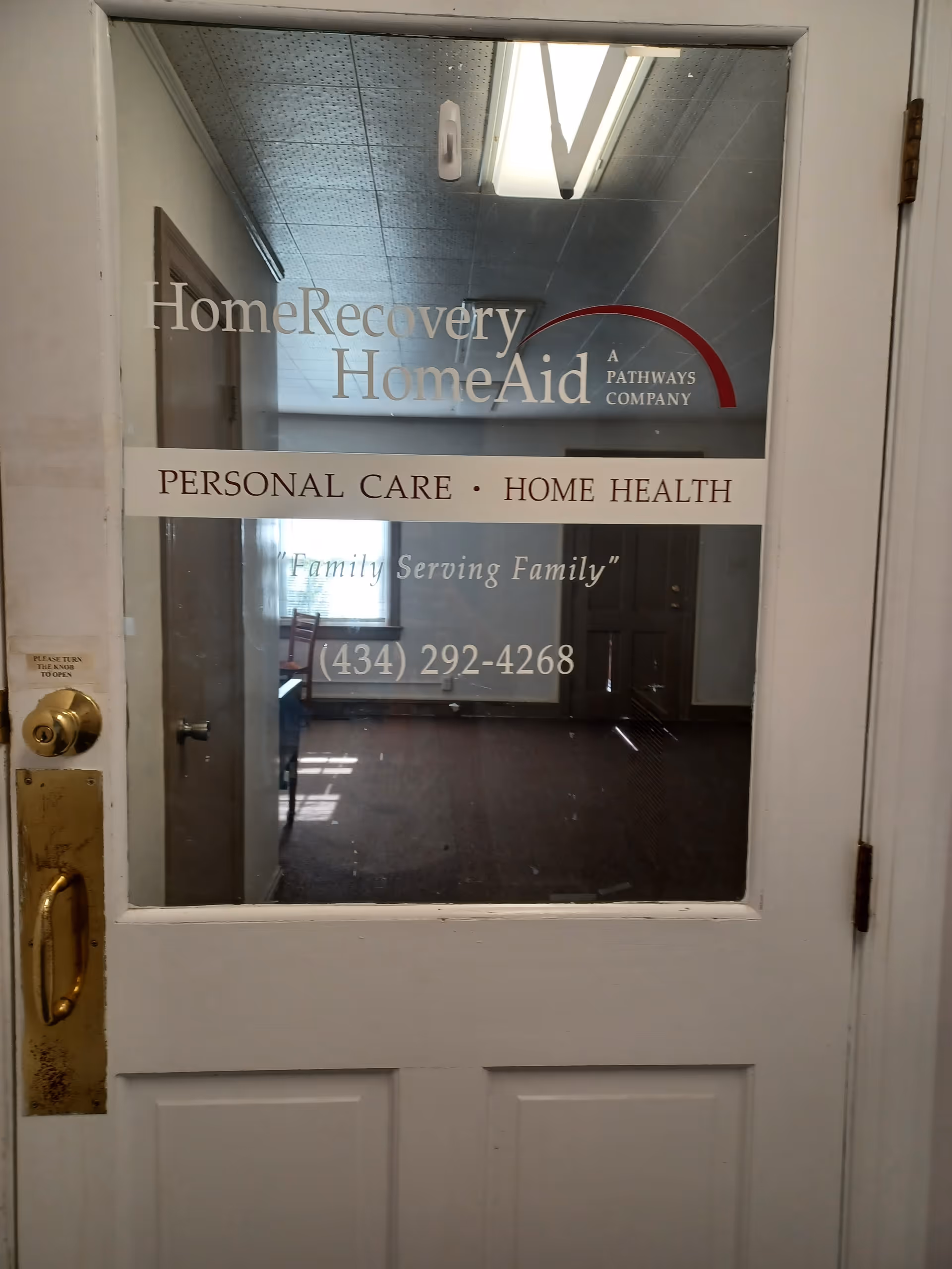 Glass door displaying Home Recovery-Home Aid signage inside a senior care facility entrance.