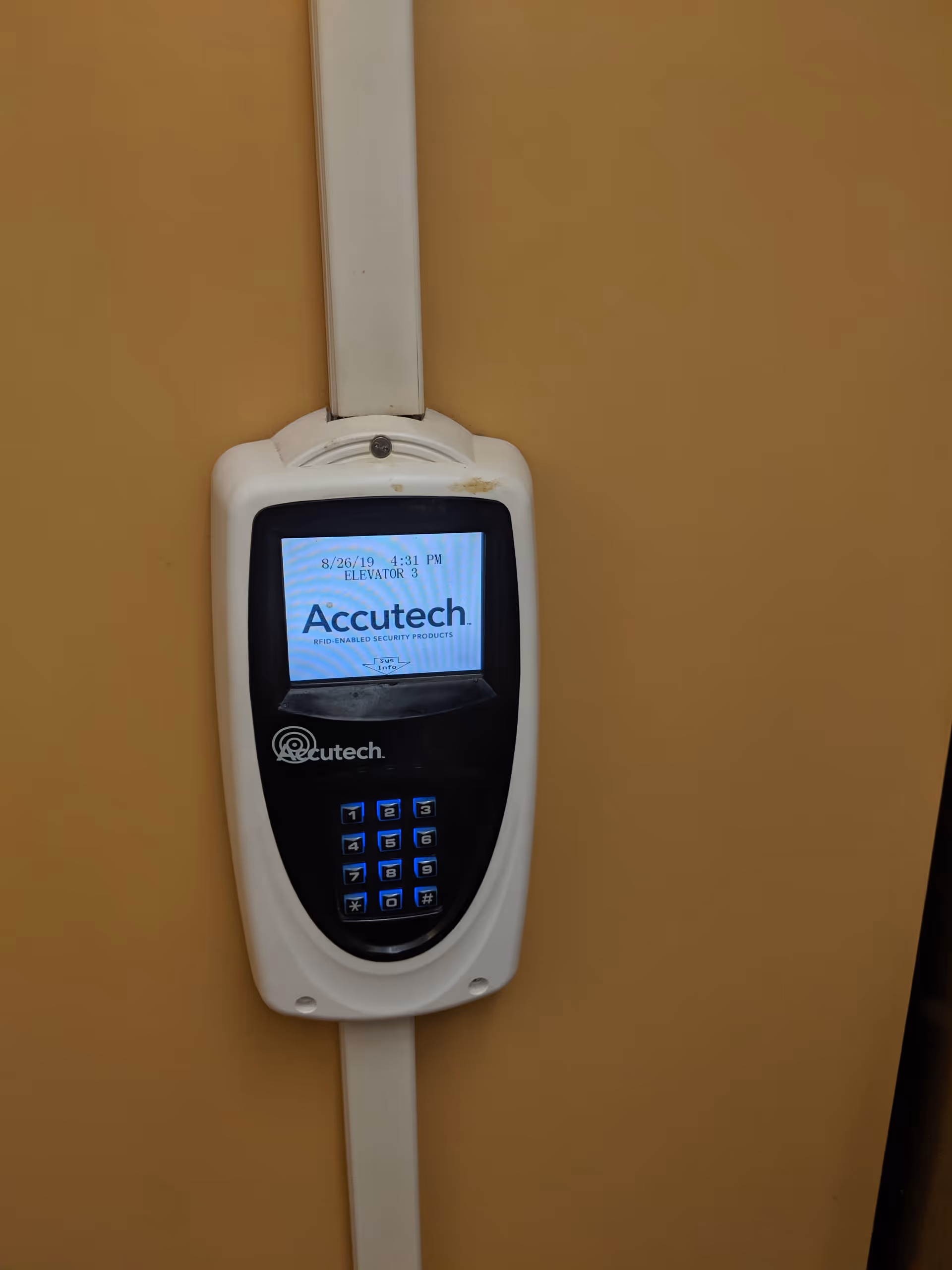 Close-up of a white Accutech security keypad mounted on a tan interior wall.