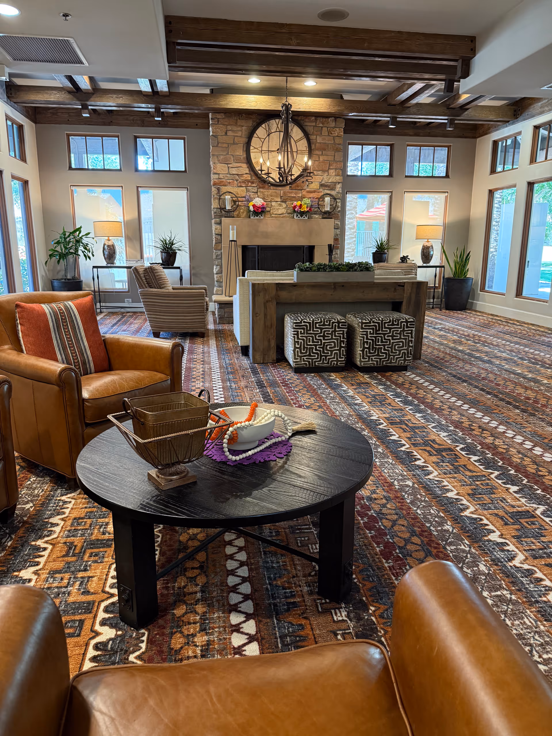 Cozy senior living lounge with leather chairs, fireplace, and circular coffee table.