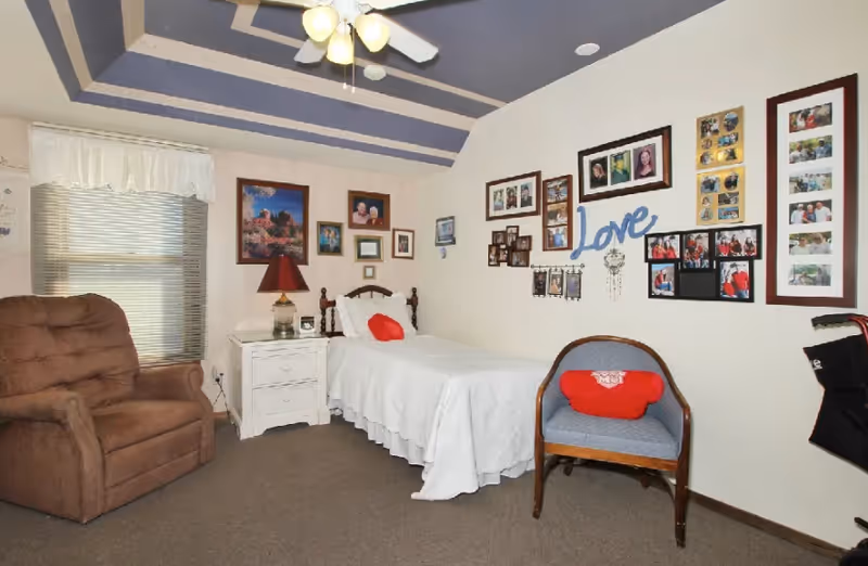 Cozy bedroom with a bed, nightstand, armchair, and wall photo collage.
